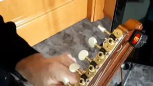 finador electrónico en el clavijero de una bandurria. Afinando una bandurria con un afinador de cabezal electrónico que muestra la nota E.